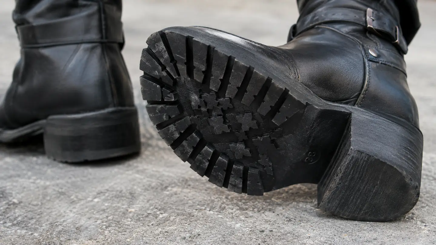 A close-up of a motorcycle boot's sole and low heel showing the tread pattern