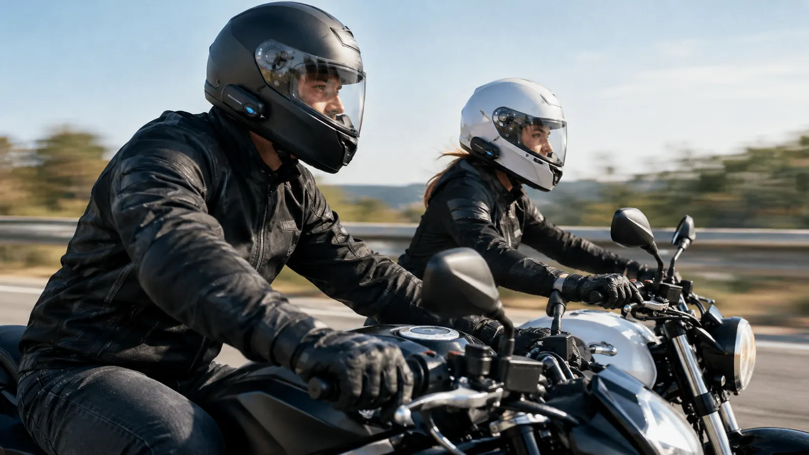 Two riders on motorcycles riding side by side on a highway, both wearing helmets with communication units